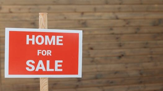 pexels-photo-8482511-8482511 Close-up of a red home for sale sign against a wooden backdrop, ideal for real estate use.